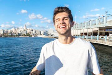Portrait of a young happy tourist man with a smile near Galata Bridge and tower in Istanbul 
