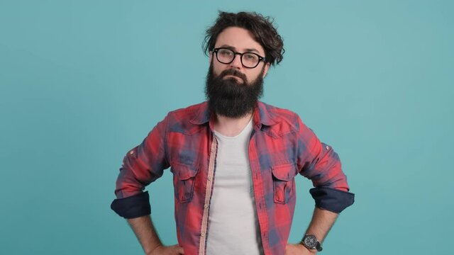 Young man with big beard annoyed with bad attitude making stop sign crossing hands, saying no, expressing security over turquoise background.