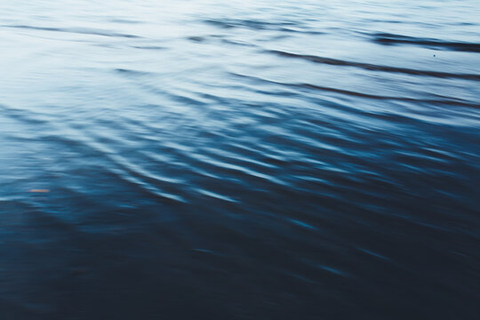 Close-up of water texture, smooth blue waves of water on the shore beach, color landscape photo of water 