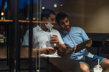 Dos jovenes mirando tablet mientras toman cafe