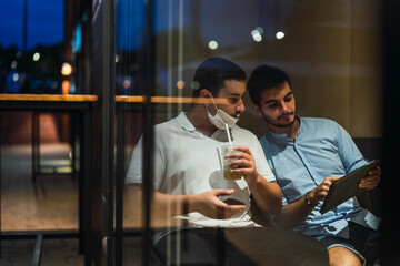Dos jovenes mirando tablet mientras toman cafe