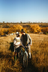 Lovely hipster couple with bike. Stylish and loving couple wearing hats and sweaters enjoying each...