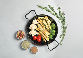 Flat lay composition with raw white carrot and vegetables in frying pan on light grey table