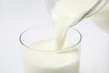 Pouring milk into glass on white background, closeup