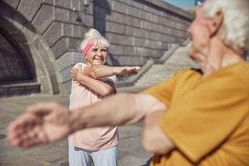Two people performing a cross-body shoulder stretch