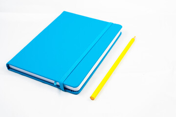 blue notebook and yellow pencil on white background. design concept