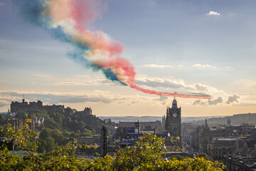 Edinburgh, Scotland, UK - August 2020: RAF Red Arrows Edinburgh Flypast with team's famous vapour trails in red, white and blue colors over Edinburgh city at sunset. Flight of Red Arrows aerobatic - obrazy, fototapety, plakaty