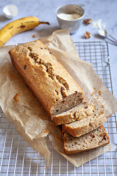 Banana bread sliced on a cooling rack with banana and flour in the background