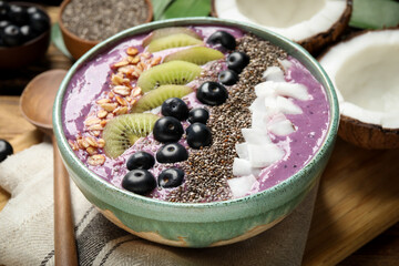 Delicious acai smoothie with fruits and chia seeds in bowl on table, closeup