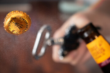 A bottle top being flipped open from a bottle of beer