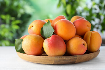 Many fresh ripe apricots on white table against blurred background