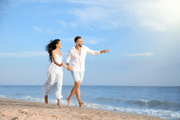 Happy young couple running together on beach