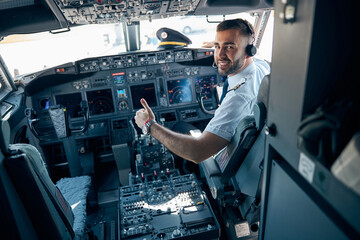 Handsome man in uniform showing like in the cabin of aircraft