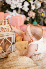 Fototapeta na wymiar Cute baby girl smiles among new year's gifts in the Christmas interior. New year's gift concept. new year 2021