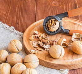 Close-up of a walnut and Nutcracker. Freshly cracked walnut in a Nutcracker on a wooden tray and...