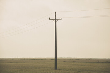 Poste eléctrico en un campo vacío con niebla