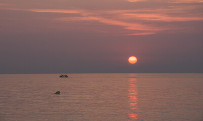 Barco en el mar durante el amanecer con sol naciente