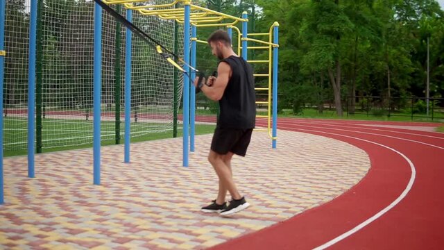 A muscular man doing legs exercise using rubber belt to force strenth of workout