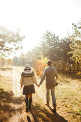Obraz premium Stylish and loving couple enjoying each other on a sunny day in the park. Hipster couple wearing beautiful hats and sweaters. The concept of youth, love, autumn and lifestyle. 