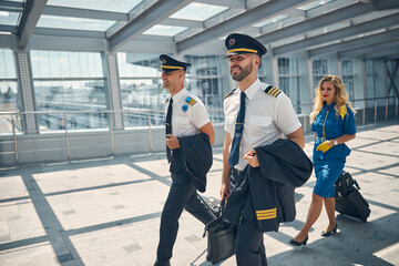 Cheerful pilots and stewardess walking through airport terminal © Svitlana