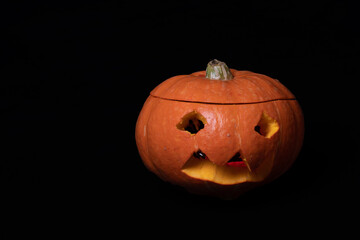 Smiling Halloween pumpkin with eyes carved from an orange pumpkin isolated on a black background