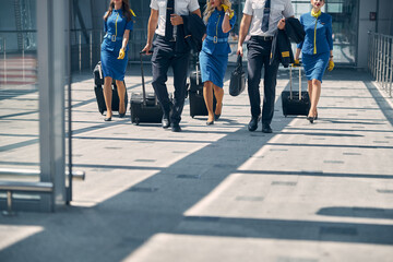 Aircrew members with travel suitcases walking in airport terminal