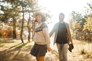 Stylish and loving couple enjoying each other on a sunny day in the park. Hipster couple wearing beautiful hats and sweaters. The concept of youth, love, autumn and lifestyle.
