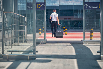 Male pilot with travel suitcase crossing the road at airport © Svitlana