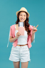 Woman traveler holding passport with ticket. Portrait of smiling happy girl on blue.