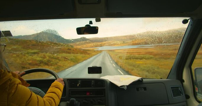 Woman drive camping van on epic mountain road. Living van life on wheels, during road trip across USA or Iceland. Female traveller drive RV van to camping site, use smartphone gps and map. Wanderlust