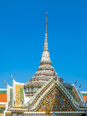 Art at facade and entrance door in The Temple of Emerald Buddha, the most beautiful landmark in Bangkok, Thailand, under summer blue sky