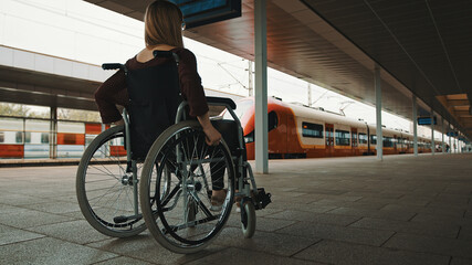 Disabled young woman waiting for a train in the wheelchair. High quality photo