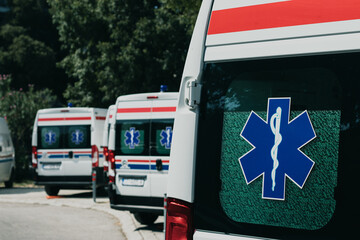 Multiple white ambulance vans parked together in Split, Croatia amid the coronavirus pandemic. Global healthcare symbol on their door windows