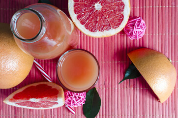 fresh grapefruit juice in a clear glass and slices of grapefruit on a red background top view 