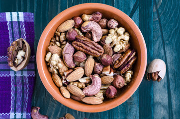 different types of nuts in a brown dish on a wooden background top view	