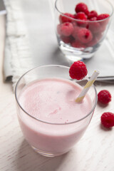 Tasty fresh milk shake with raspberry on white table, closeup