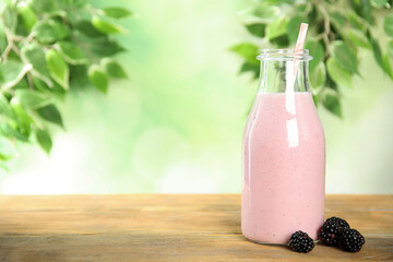 Tasty fresh milk shake and blackberries on wooden table. Space for text