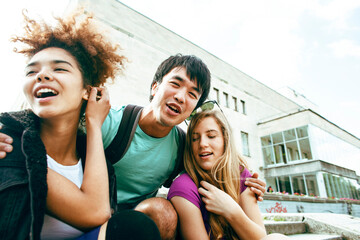 cute group of teenages at the building of university with books huggings, diversity nations, having lunch