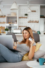 Young businesswoman at home makes a purchase on the Internet. Beautiiful woman on the laptop with credit card.