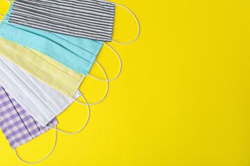 Homemade protective face masks on yellow background, flat lay. Space for text