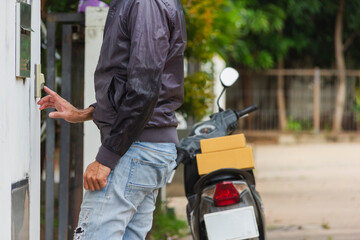 delivery man wear hygienic mask and blue cap pushing bell and holding cardboard box with look to customer for receive