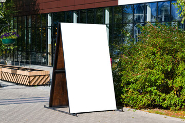 Empty white advertising layout on a city street in summer.Advertising wooden Billboard with a copy of the space.mock up, illuminated by the sun.