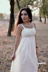 Fototapeta na wymiar Long-haired brunette in a white dress in the woods