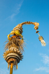 balinese penjor decorating the streets during galungan and kuningan celebration with a blue sky background