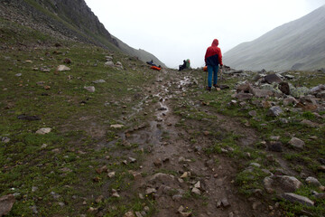 Fototapeta premium Tourists on a mountain pass in foggy and rainy weather. Mountain crossing. Caucasus. 