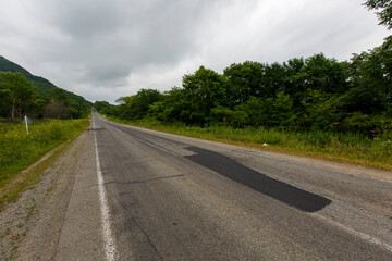 Very bad road in Russia. The asphalt road is all in holes in the middle of the forest.