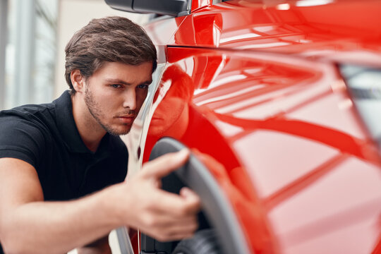 Young Man Checking New Car In Salon