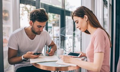Colleagues working in cafe with smartphones and notebooks