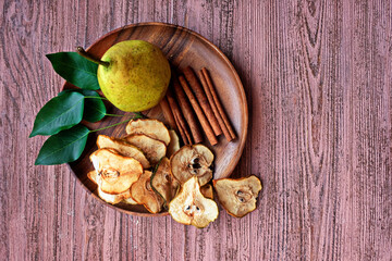 Cinnamon pear chips with fresh pears  Dried fruits. Healthy sweet snack. Vegetarian Vegetarian appetizer on a wooden plate.