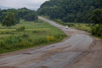 Very bad road in Russia. The asphalt road is all in holes in the middle of the forest.